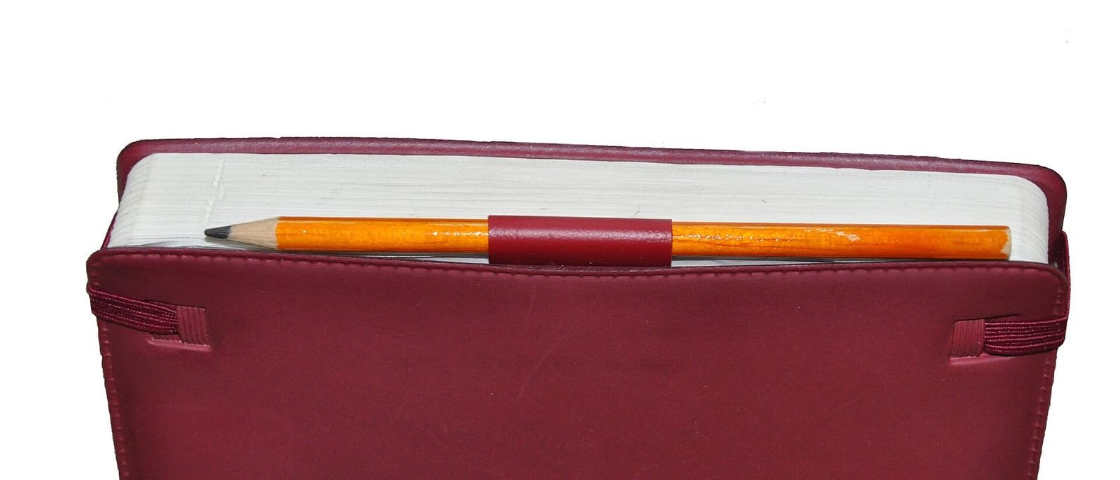 Closed red appointment diary with a pencil tucked into its pen loop