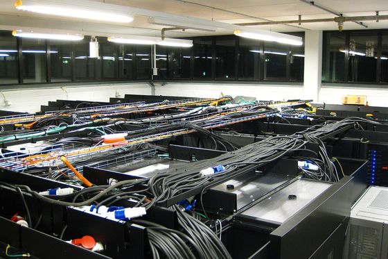Server room with rows of black racks, cable trays and bundled power cables