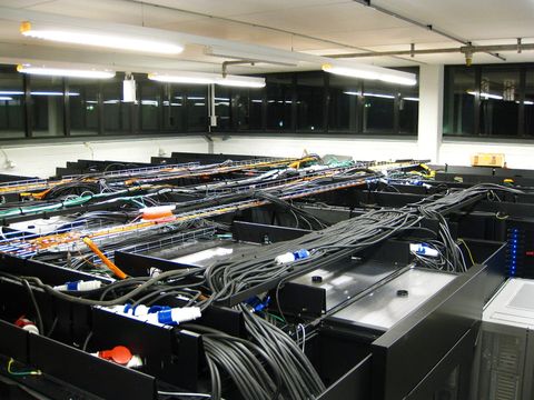 Serverraum mit Reihen schwarzer Racks, Kabeltrassen und vielen gebündelten Stromkabeln