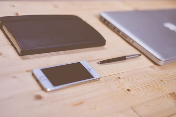 Smartphone, pen, notebook and closed laptop on a wooden table