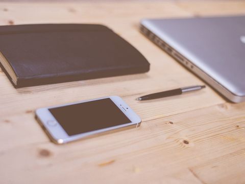 Smartphone, pen, notebook and closed laptop on a wooden table
