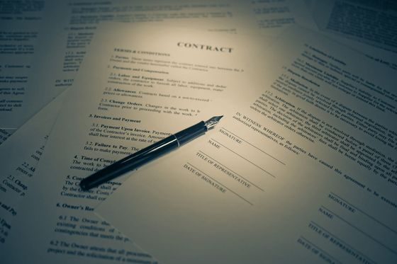 Printed contract with signature lines and a fountain pen lying across it