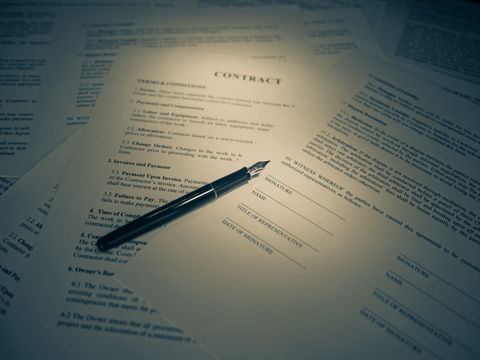 Printed contract with signature lines and a fountain pen lying across it
